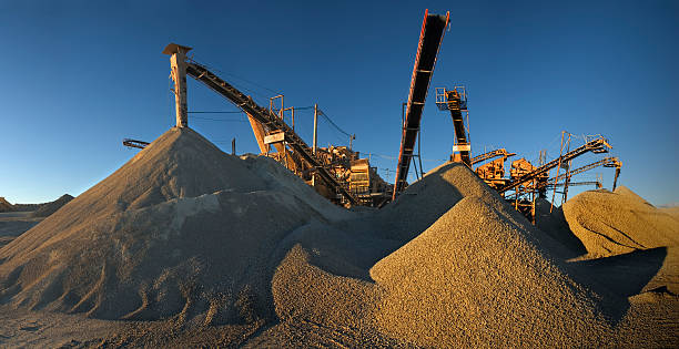 Panoramic image of a gravel mine before sunset. Big machinery and a lot of sand and gravel.